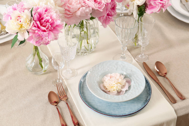 Stylish table setting with beautiful peonies and golden cutlery - Фото, изображение