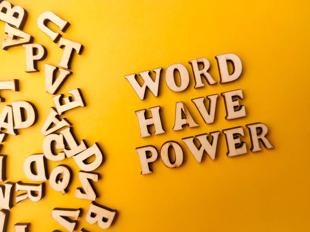 Close-up houten brief speelgoed geregeld het woord WORD HEBBEN KRACHT met een gele achtergrond. - Foto, afbeelding