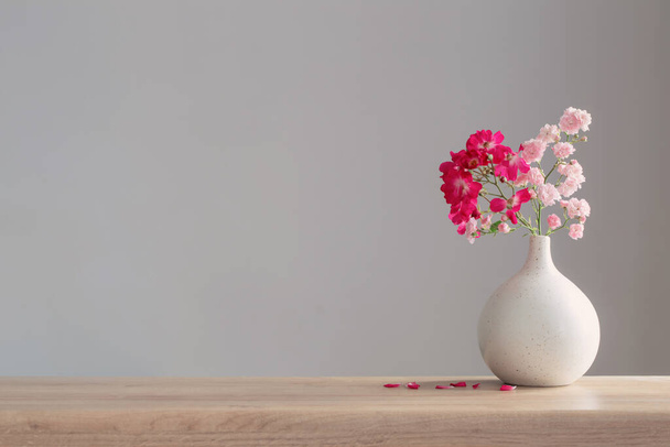 pink roses in ceramic vase on wooden table - Φωτογραφία, εικόνα