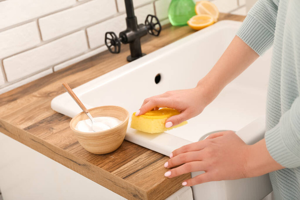 Woman cleaning white sink with sponge and baking soda - Foto, Imagem