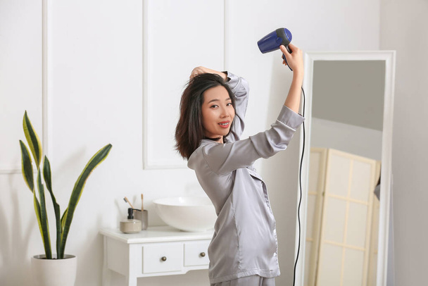 Bastante joven mujer asiática secando el pelo en el baño - Foto, imagen