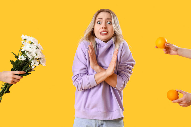 Alergická mladá žena a ženské ruce s alergeny na žlutém pozadí - Fotografie, Obrázek