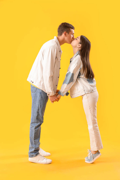 Happy young couple kissing on yellow background - Foto, imagen