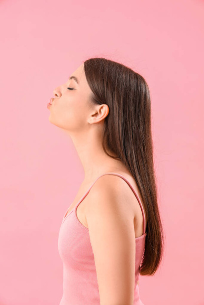 Mladá žena foukání polibek na růžovém pozadí - Fotografie, Obrázek