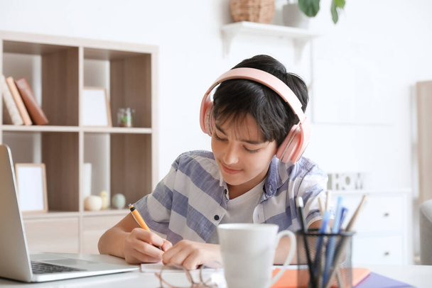 Kleiner Junge mit Kopfhörern lernt zu Hause - Foto, Bild