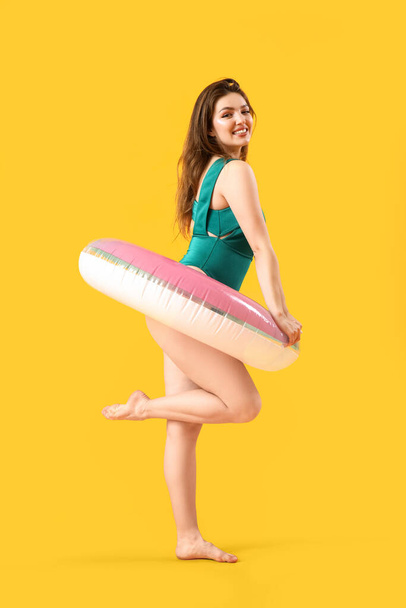 Young woman with swim ring on yellow background - Zdjęcie, obraz