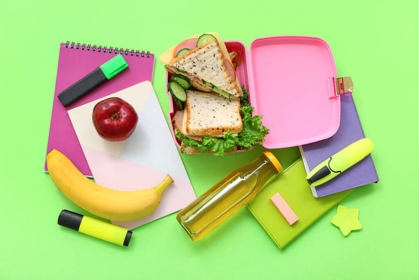 Různé papírnictví, pití a oběd box s chutným jídlem na zeleném pozadí - Fotografie, Obrázek