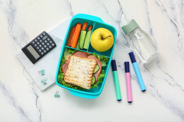 Канцелярские принадлежности, напитки и обеденная коробка с вкусной едой на гранж белом фоне - Фото, изображение