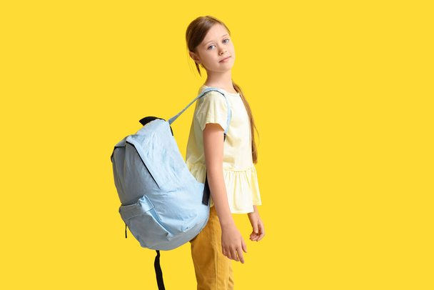 Little girl with backpack on yellow background - Φωτογραφία, εικόνα