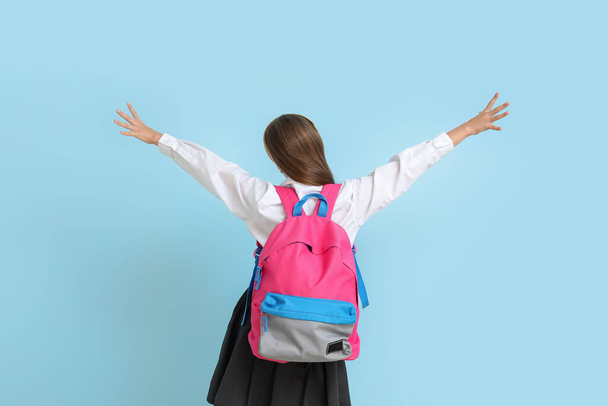 Kleines Schulmädchen mit Rucksack auf blauem Hintergrund, Rückseite - Foto, Bild