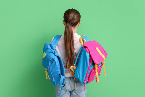Little girl with backpacks on green background, back view - Photo, Image