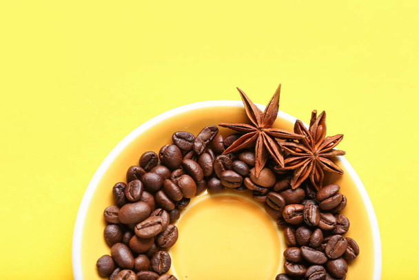 Frame made of coffee beans and star anise on yellow background - Photo, Image