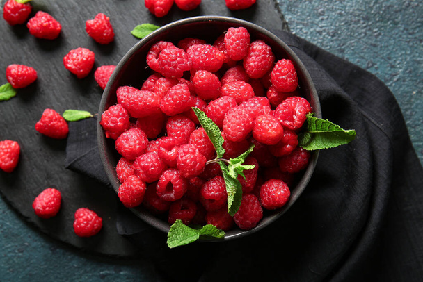 Bowl and board with fresh raspberries on dark background - Foto, afbeelding