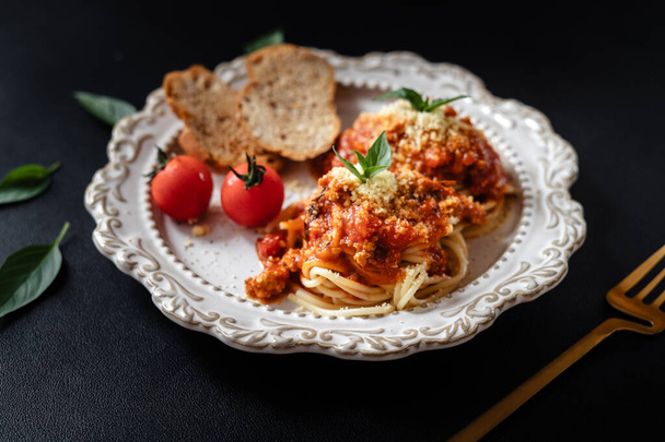 Spaghetti mit Tomatensauce und Käse auf schwarzem Hintergrund - Foto, Bild
