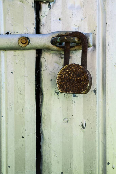 Close-up of rusted heavy duty security padlock on silver metal door, background image - Foto, Bild
