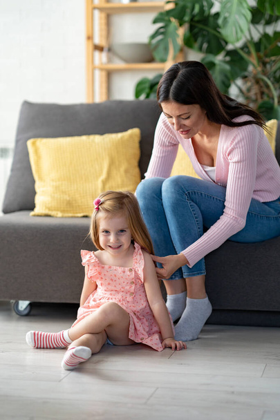 happy mother and daughter in living room spending time together - Zdjęcie, obraz