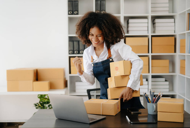 Small business entrepreneur SME freelance African woman working at home office with boxes,tablet and laptop , e-commerce concept - Foto, Imagem