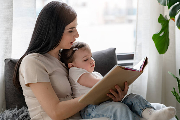 happy mother and daughter reading book at home - Foto, imagen