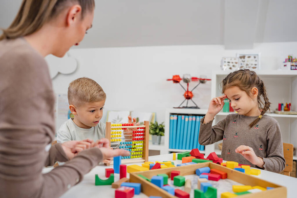 Vrolijke kinderen spelen met kleurrijk didactisch speelgoed in een kleuterschool. Speel met educatief speelgoed. Spelenderwijs leren. - Foto, afbeelding