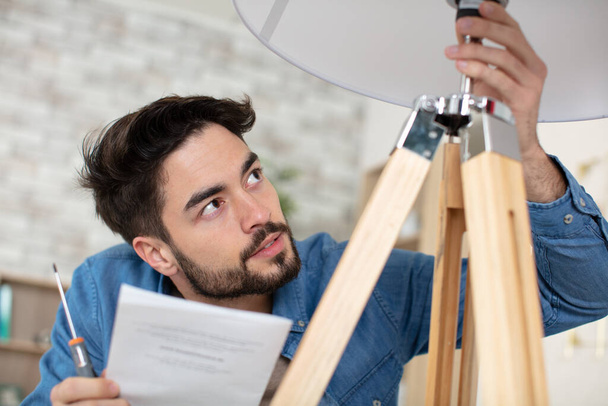 man changing light bulb in pendant lamp indoors - 写真・画像
