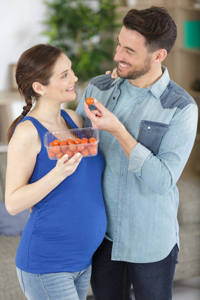 couple in kitchen interior with basket of fresh tomatoes - Foto, imagen