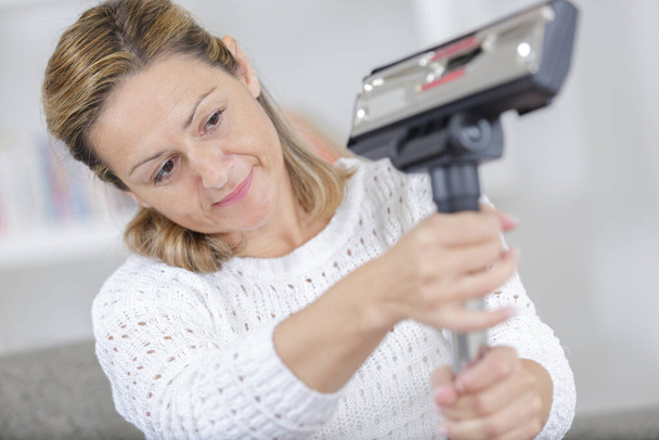 woman fixing the vacuum cleaner at home - Foto, Bild