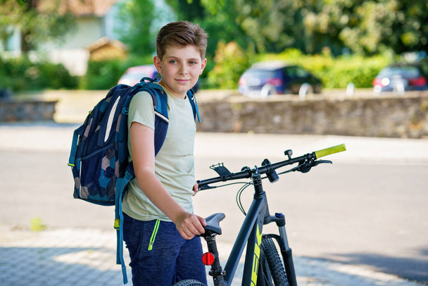 Handsome preteen boy going to school on bike. Teenager ride bicycle. Safe way to high school. Happy child boy with backpack on bike. Healthy outdoor activity for young student - Photo, Image