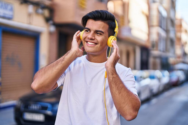 Young hispanic man listening to music at street - Photo, Image