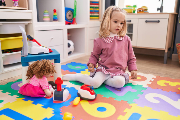 Adorable blonde girl playing supermarket toys sitting on floor at kindergarten - Photo, Image