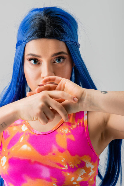 divat előre, tetovált fiatal nő kék haj pózol a kezét közel arc szürke háttér, individualizmus, modern stílus, városi divat, élénk szín, női modell, nézi kamera - Fotó, kép