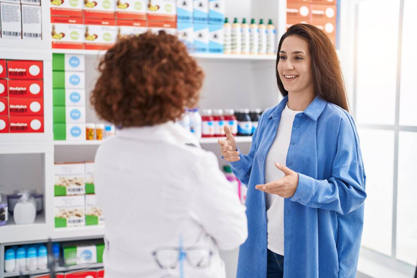 Two women pharmacist and customer speaking at pharmacy - Foto, Bild