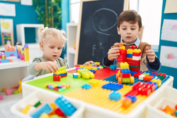 Adorable boy and girl playing with construction blocks sitting on table at kindergarten - Fotografie, Obrázek