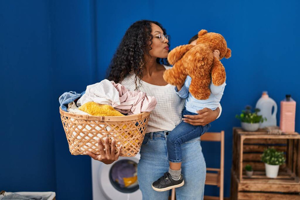 洗濯室で洗濯機を待っているテディベアで遊ぶ母親と息子 - 写真・画像