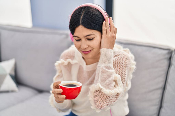 Young chinese woman listening to music drinking coffee at home - Φωτογραφία, εικόνα
