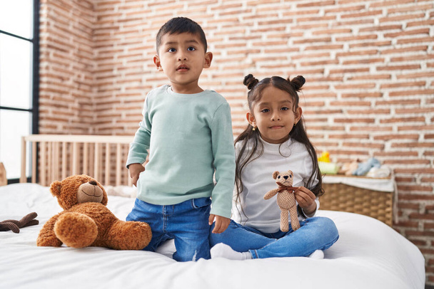 Adorable boy and girl smiling confident holding teddy bear at bedroom - Foto, afbeelding