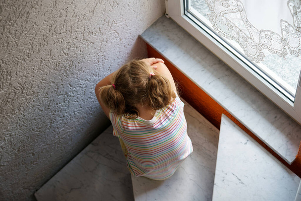 Magányos kis óvodás lány otthon. Szomorú gyermek egyedül. Érzelmi stressz a gyermekek, az iskola és a családi problémák - Fotó, kép
