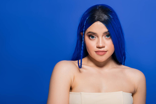 modern beauty concept, young woman with dyed hair posing on blue background, hair color, individualism, female model with makeup and trendy hairstyle, vibrant youth, skin perfection  - Photo, Image