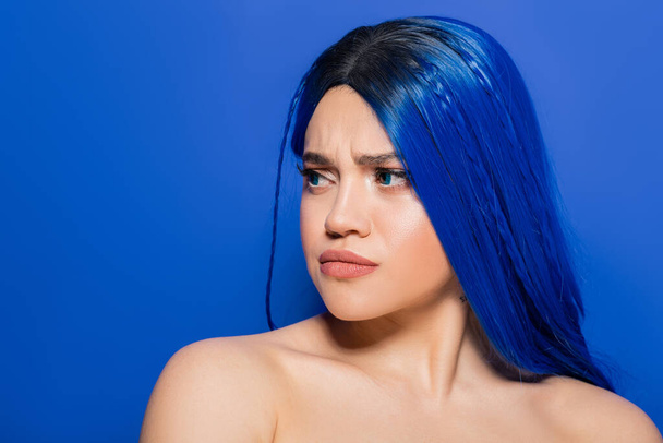 πορτρέτο της δυσαρεστημένης γυναίκας με βαμμένα μαλλιά κοιτάζοντας μακριά στο μπλε φόντο, το χρώμα των μαλλιών, ατομικισμός, θηλυκό μοντέλο με μακιγιάζ και μοντέρνο χτένισμα, ζωντανή νεολαία, συναισθηματική  - Φωτογραφία, εικόνα