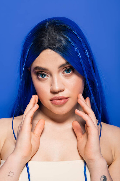 modern subculture, self expression, portrait of young woman with dyed hair posing on blue background, hair color, individualism, female model with makeup and trendy hairstyle  - Fotó, kép