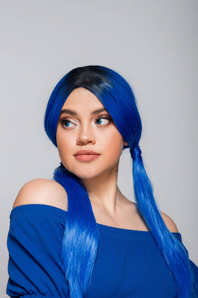 modré vlasy, mladá žena s modrýma očima a vlasy upřené na šedé pozadí, individualismus, sebevyjádření, trendy krásy, moderní subkultura, make-up a účes - Fotografie, Obrázek