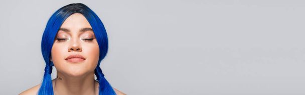 moderne Subkultur, tätowierte Frau mit geschlossenen Augen und blauen Haaren, die auf grauem Hintergrund posiert, Frisur, lebendige Farbe, moderne Schönheit, Selbstausdruck, Individualismus, Banner - Foto, Bild