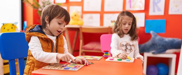 Uroczy chłopiec i dziewczyna gra logiczna matematyki gry siedzi na stole w przedszkolu - Zdjęcie, obraz