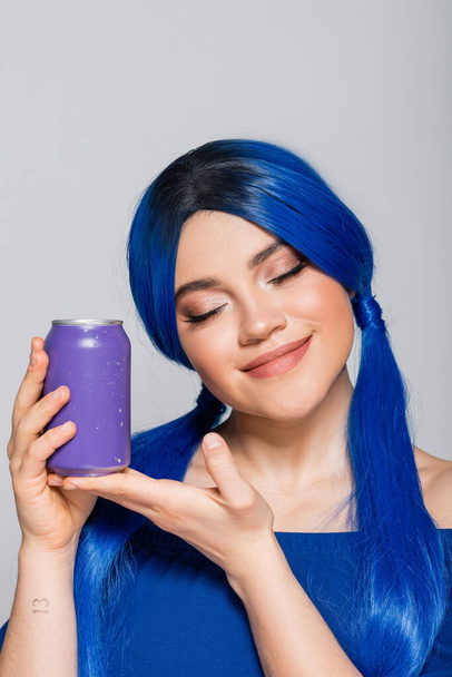 Sommerkonzept, erfreut junge Frau mit blauen Haaren, die Getränkedose auf grauem Hintergrund hält, Individualismus, Jugend und Lifestyle, lebendige Farbe, Selbstausdruck, einzigartige Identität, moderne Subkultur  - Foto, Bild