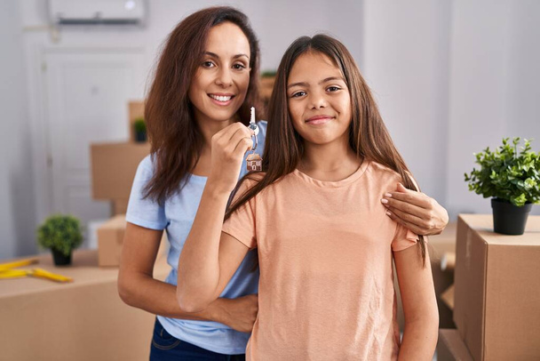 Woman and girl mother and daughter holding key at new home - Foto, Imagen