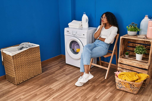 Jeune femme latine ennuyeux attendant la machine à laver à la buanderie - Photo, image