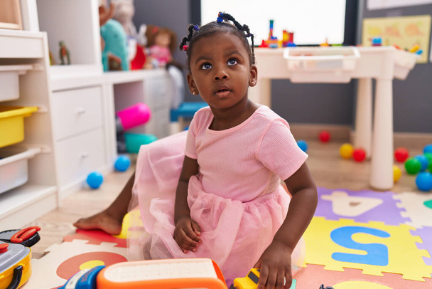 African american girl playing with car toy sitting on floor at kindergarten - Foto, imagen