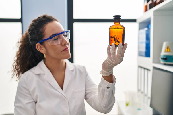 Jeune belle femme hispanique scientifique tenant le tube à essai avec la plante au laboratoire - Photo, image