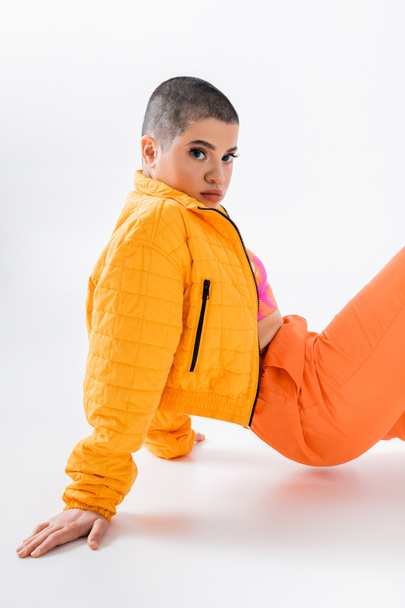 urban fashion, young woman in colorful clothes posing on grey background, looking at camera, urban style, individualism, vibrant and youthful energy, urban fashion, generation z - Foto, Imagen