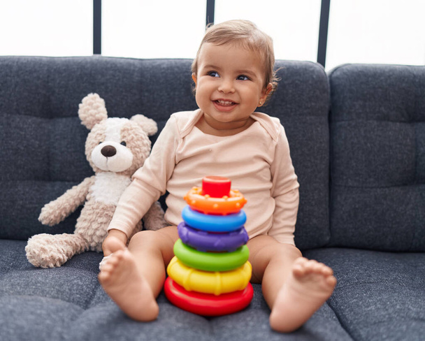 Adorável bebê hispânico brincando com aros jogo sentado no sofá em casa - Foto, Imagem
