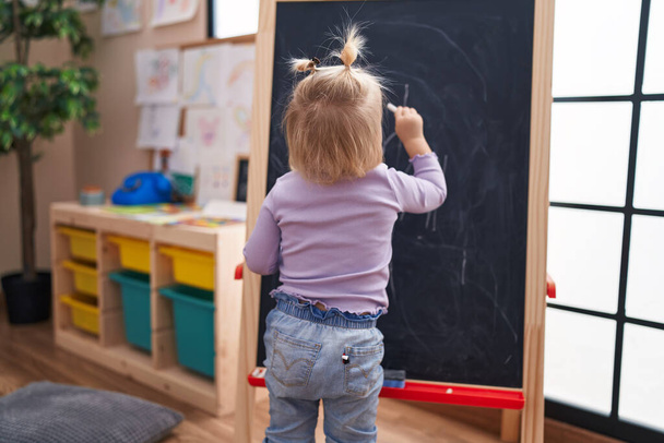 Adorable blonde girl preschool student drawing on blackboard at kindergarten - Zdjęcie, obraz